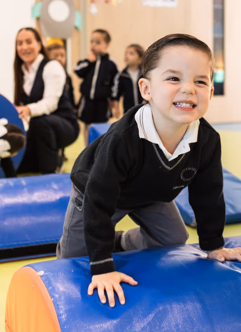 Niños sonrientes sentados en escalones con uniforme escolar deportivo.